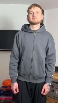 Szürke cipzáras pulóver kenguruzsebbel, puha anyagból készült. Kapucnival és diszkrét logóval a mellkasnál. Laza fazon.