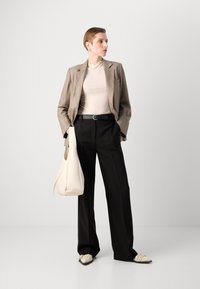 Grauer Karoblazer, beige geripptes Oberteil, schwarze weite Hosen, cremefarbene Handtasche und gemusterte Slippers. Glatte Texturen und strukturiertes Design.
