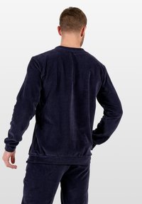 Granatowa bluza sztruksowa z prążkowaną fakturą, długimi rękawami i luźnym krojem z szeroką gumą w pasie.