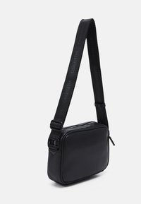 Svart lädercrossbodyväska med rektangulär form, med en texturerad yta och ett bärrem med det präglade varumärket.