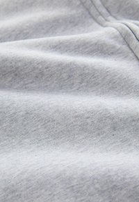 Tejido gris claro con una superficie suave y ligeramente texturizada. Presenta fibras suaves y una variación de color sutil a lo largo del material.