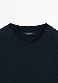 Pull bleu marine foncé à col rond, col côtelé et une étiquette noire indiquant « Massimo Dutti Made in China. »