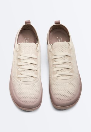 Paar beige Stricksneaker mit Schnürung vorne, gepolsterten Innensohlen und Zuglaschen an den Fersen, von oben auf weißem Hintergrund gezeigt.