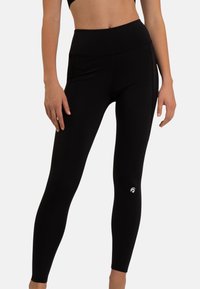 Zwarte leggings van rekbaar materiaal met een hoge tailleband, een gladde textuur en een klein wit logo nabij het onderste deel van het linkerkuit.