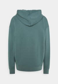 Hoodie i dovet teal, med ribbade muddar och fåll. Slät textur med en avslappnad passform och minimala sömnadsdetaljer.