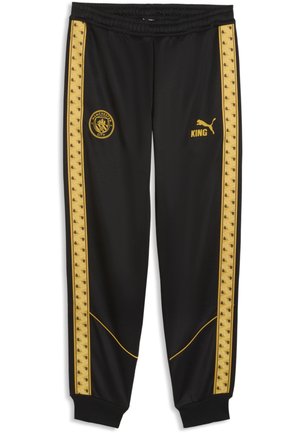 Czarne spodnie sportowe ze złotymi paskami po bokach, logo Manchester City na lewym udzie, logo Puma i tekst "KING" na prawym udzie.
