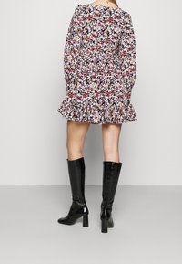 Abito floreale a maniche lunghe con orlo arricciato, caratterizzato da uno sfondo nero e fantasie di fiori colorati. Abbinato a stivali neri lucidi fino al ginocchio.