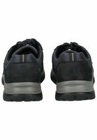 Scarpe da ginnastica nere con un mix di pelle scamosciata e tessuto, dotate di una suola grigia ammortizzata, punta arrotondata e due strisce grigie verticali sul tallone.