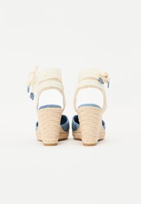 Beige espadrille-hæler med blå denim-detaljer, flettet jute-hæl, justerbar stropp med sløyfedetalj og åpen bakdesign.