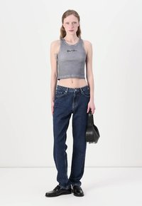 Grijze cropped tanktop, donkerblauwe loszittende jeans, zwarte schoenen, met een kleine zwarte tas. Eenvoudig ontwerp met minimale details.
