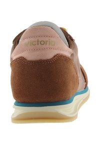 Zapatilla de ante marrón y rosa con suela azul y blanca, vista desde atrás, mostrando el logo "victoria" en la lengüeta rosa del talón.