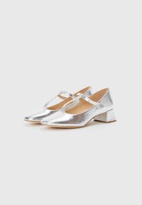 Silver metallic Mary Jane shoes with a pointed toe, small block heel, and an adjustable strap across the instep. Smooth texture.