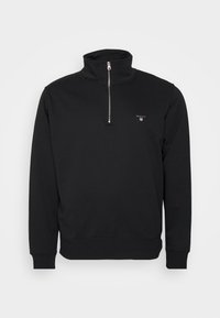 Zwart sweatshirt met rits en opstaande kraag, gemaakt van zachte stof. Heeft ribgebreide manchetten en onderrand, met een klein logo op de borst. Minimalistisch ontwerp.