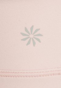 Um tecido rosa claro apresenta um discreto padrão de flores estilizadas em verde menta. A vista em close destaca a textura suave e os detalhes de costura cuidadosa.