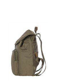 Zaino verde oliva con forma strutturata, materiale in tessuto, spallacci regolabili, tasche laterali e chiusura a ribalta.