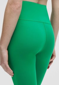 Högmidjade gröna leggings tillverkade av stretchigt material, med en slät yta, platta sömmar och en figurnära design.