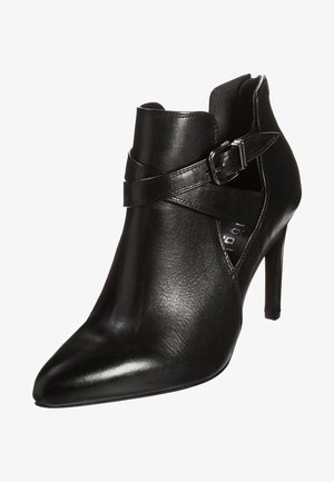 Černá kožená kotníková bota s špičatou špičkou, vysokým jehlovým podpatkem a nastavitelným páskem s detailní sponou ve stříbrné barvě.