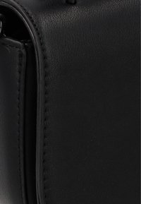 Borsa in pelle nera con superficie testurizzata, bordi puliti e doppia cucitura per una maggiore durata. Forma rettangolare compatta.