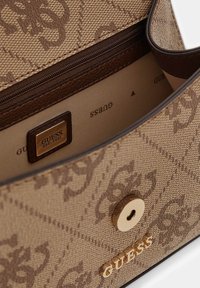 Brązowa torebka w wzory z zamkiem błyskawicznym i złotym logo. Wnętrze beżowe z złotą metką z logo.