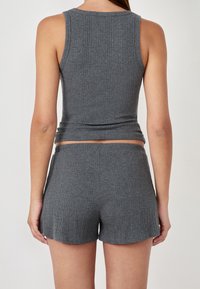 Top de tirantes gris acanalado combinado con pantalones cortos acanalados a juego, con un diseño ajustado y textura suave. Sin patrones visibles ni herrajes.