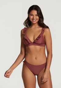 Bordeaux bikini set met een v-hals top met ruches op de schouderbanden en bijpassende low-rise onderbroekjes met ruches aan de zijkanten.