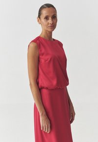 Red sleeveless dress with a relaxed fit, round neckline, and elastic waist. Textured fabric and side pocket detail.