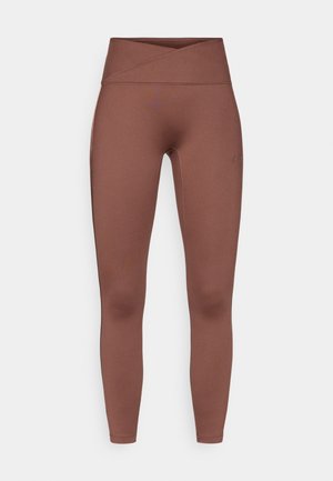 Leggings marrones de cintura alta con una textura suave y elástica. Presentan una cinturilla cruzada y sin costuras visibles. Apta para ropa de deporte.