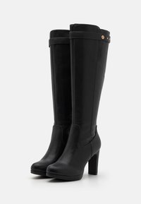 Black knee-high boots made of smooth leather with a rounded toe and a block heel. Features a decorative strap and metal accents.