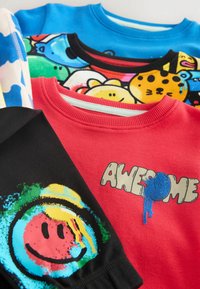 Fyra crewneck-tröjor i olika färger: blå, röd, svart och vit. Varje tröja har unika grafiska mönster och lekfulla detaljer.