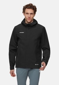 Czarna wodoodporna kurtka z kapturem, z zamkiem błyskawicznym z przodu, bocznymi kieszeniami i logo Mammut oraz Gore-Tex na klatce piersiowej i dolnej krawędzi.