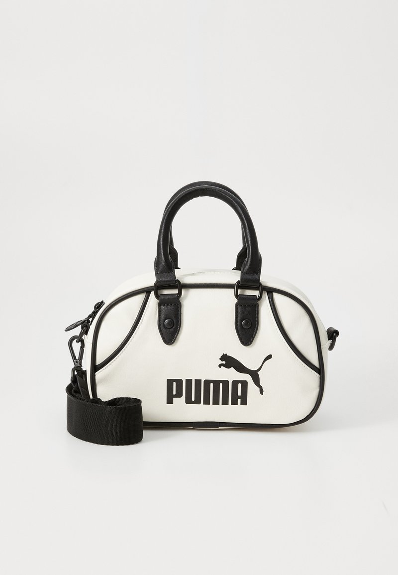 White handbag with black accents, featuring a Puma logo. Short, rounded handles and a detachable strap, made from textured synthetic material.