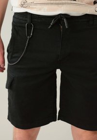 Pantaloni corti neri in cotone misto con vestibilità rilassata. Include una vita con coulisse, tasche laterali e un attacco per clip.