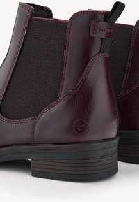 Bottines Chelsea en cuir bordeaux foncé avec panneaux latéraux élastiques, languettes de tirage et semelles basses en caoutchouc noir empilées, vues de dos et de côté.