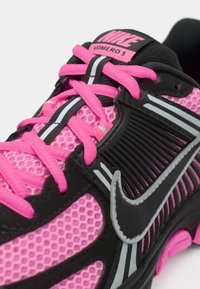 Bežecká obuv Nike Vomero 5 v ružovej a čiernej sieti s jasne ružovými šnúrkami a reflexnými striebornými detailmi po stranách a na jazyku.