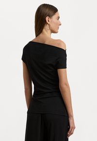 Black off-shoulder top with short sleeves, made of smooth fabric. Features a fitted silhouette with draped detailing at the back.