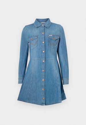 Blauwe denim jurk met lange mouwen, knopen aan de voorkant, twee borstzakken en een uitlopende rok. Voorzien van koperen knopen en contrasterende stiksels.