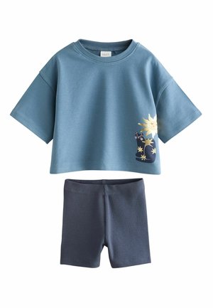 Blå kortærmet croppet skjorte med sol- og månegrafik kombineret med mørkeblå ribbede shorts.