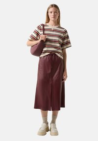 Striped short-sleeve top in cream, red, and navy. Burgundy faux leather midi skirt with drawstring waist. Beige chunky slip-on shoes.