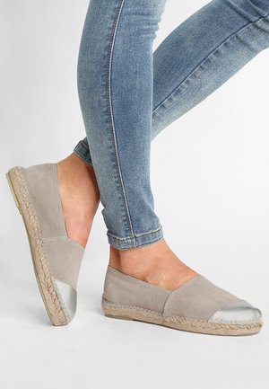 Jasnoszare espadryle z metalicznym srebrnym noskiem, o fakturowanym wykończeniu i plecioną podeszwą z juty, zestawione z niebieskimi dżinsami.