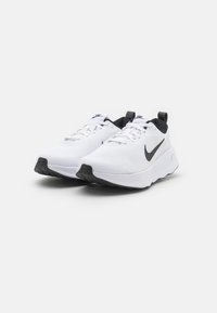Nike running shoes featuring a white mesh upper, black accents, a cushioned sole, and a flat black rubber outsole for traction.