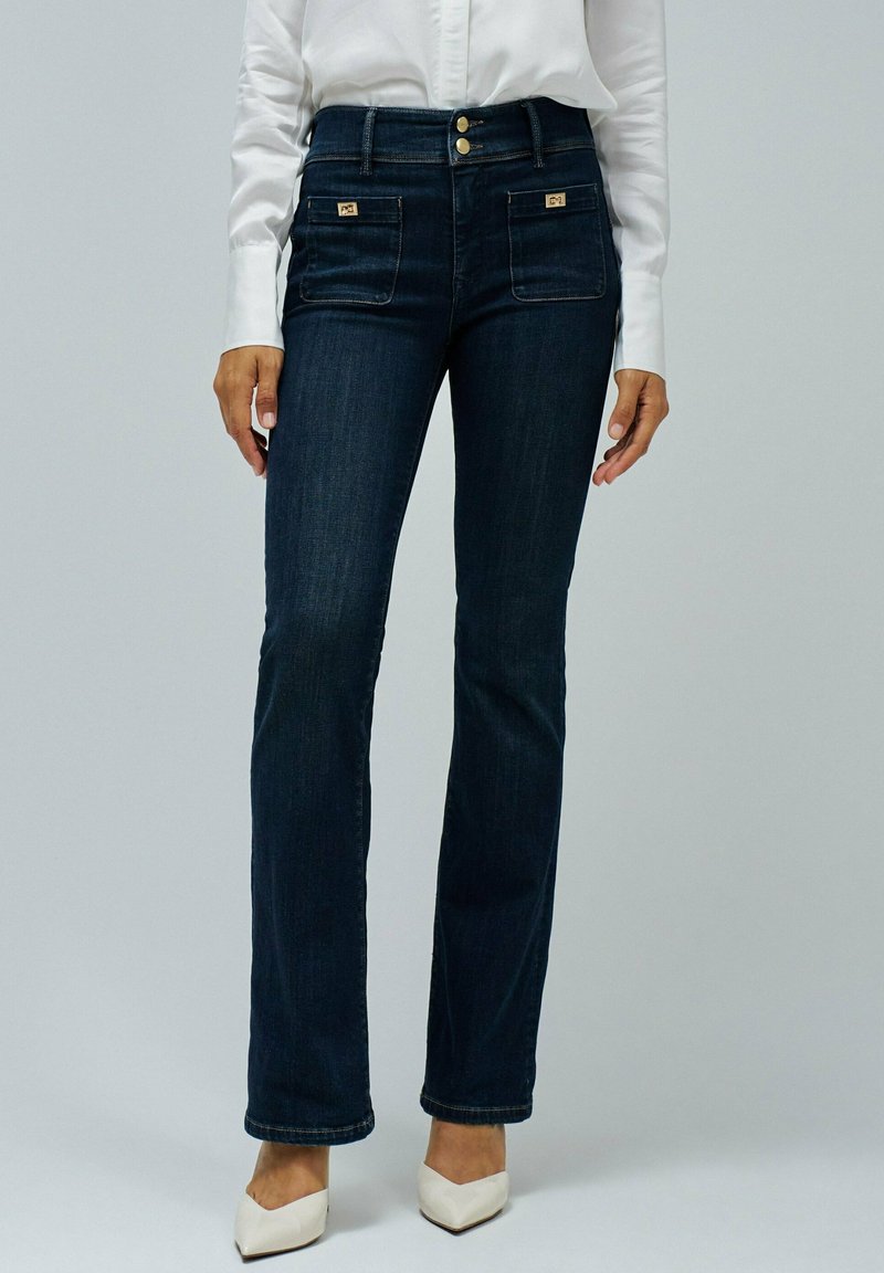 Jeans de mezclilla azul oscuro con corte recto, que cuentan con dos bolsillos frontales con herrajes dorados y una cintura alta con tres botones.