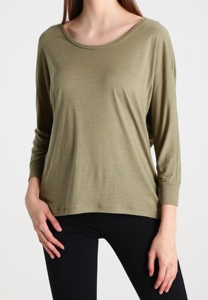 Maglietta a maniche lunghe verde oliva in un tessuto morbido e leggero. Presenta un ampio scollo e una vestibilità rilassata con maniche con polsini.