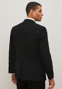 Black tailored suit jacket with a single vent at the back, notched lapels, and buttoned cuffs. Smooth fabric and structured fit.