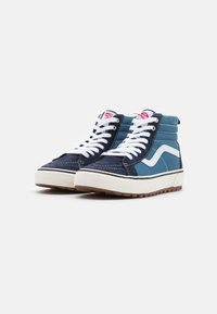 Høytop sneakers med marineblå og teal paneler, hvite detaljer og en teksturert gummisåle. Snøringene er hvite og de har en rund tunge.