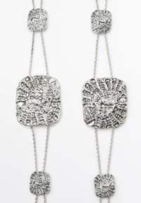 Sölvfärgad halsband med texturerade, fyrkantiga länkar med intrikata mönster, sammanlänkade av fina kedjesträngar.