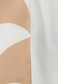 T-shirt met een wit en lichtbeige kleurblok ontwerp met een gladde, licht glanzende textuur, die grote abstracte vormen benadrukt.