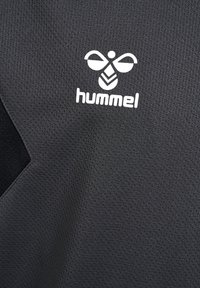 Zwart sportshirt met een textuurafwerking. Heeft een wit "hummel" logo en een opvallend honingbijontwerp op de borst.