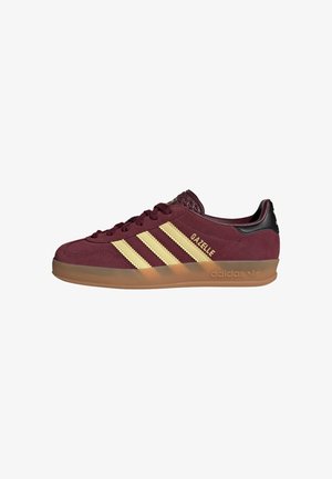 Vinrøde Adidas Gazelle sneaker med beige striber, gummisål, sort hælflig og guldlogo på siden og tungen.