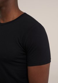 Zwart T-shirt met korte mouwen, gemaakt van een gladde katoenstof, met een ronde halslijn en een getailleerd ontwerp dat de schouder- en armzone benadrukt.