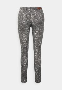 Pantalon slim avec motif peau de serpent gris et noir, avec poches arrière et petite étiquette de marque marron sur la ceinture.